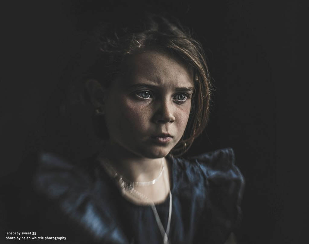 young girl with a serious expression dark background dark dress confused thinking Lensbaby Top 12 Photos
