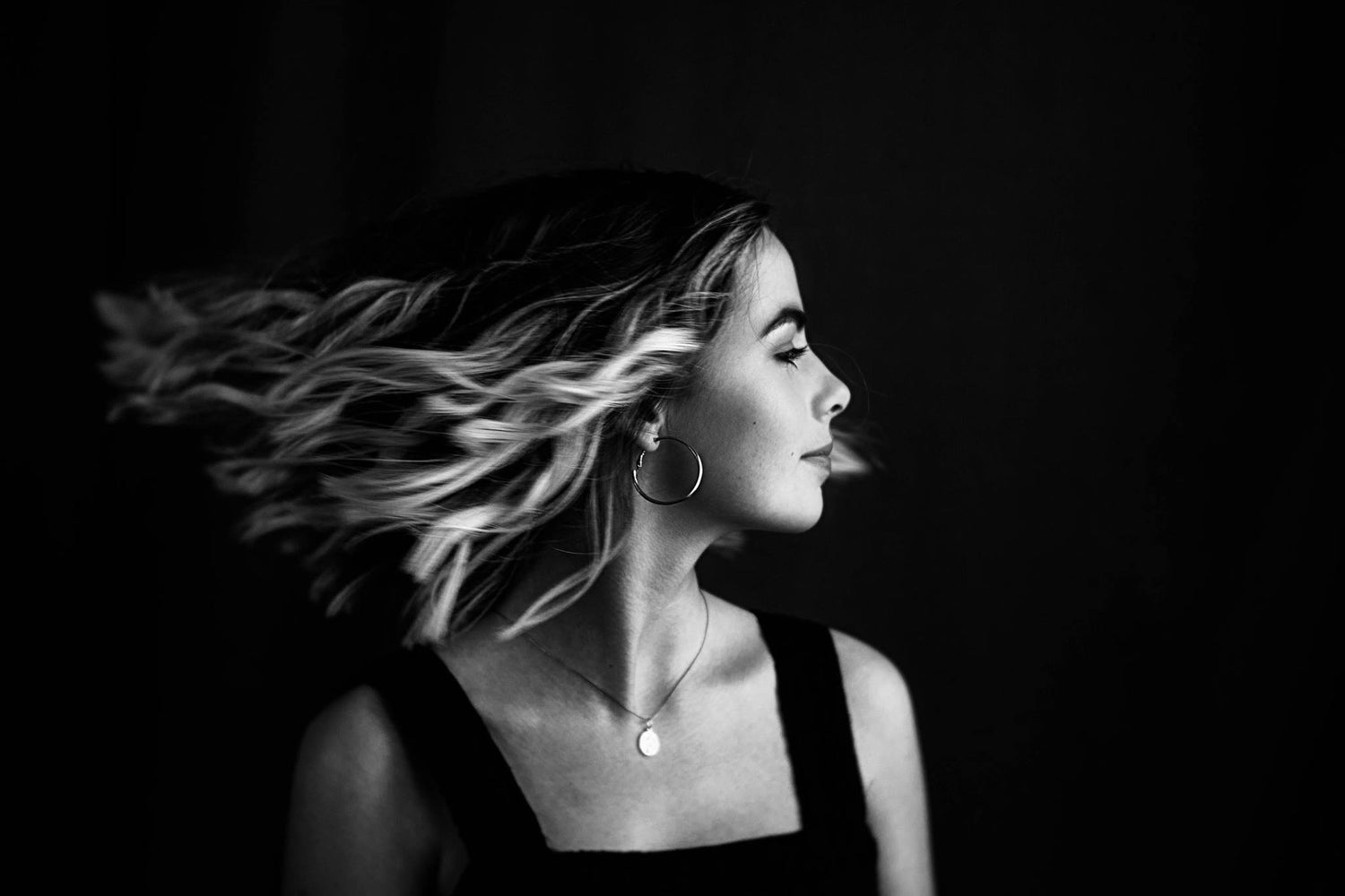 woman in black and white hair toss black tank top black background contrast Lensbaby featured photos portrait