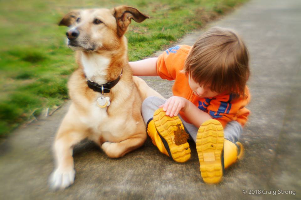 kid in yellow boots orange tshirt with brown dog sitting on a sidewalk lensbaby history
