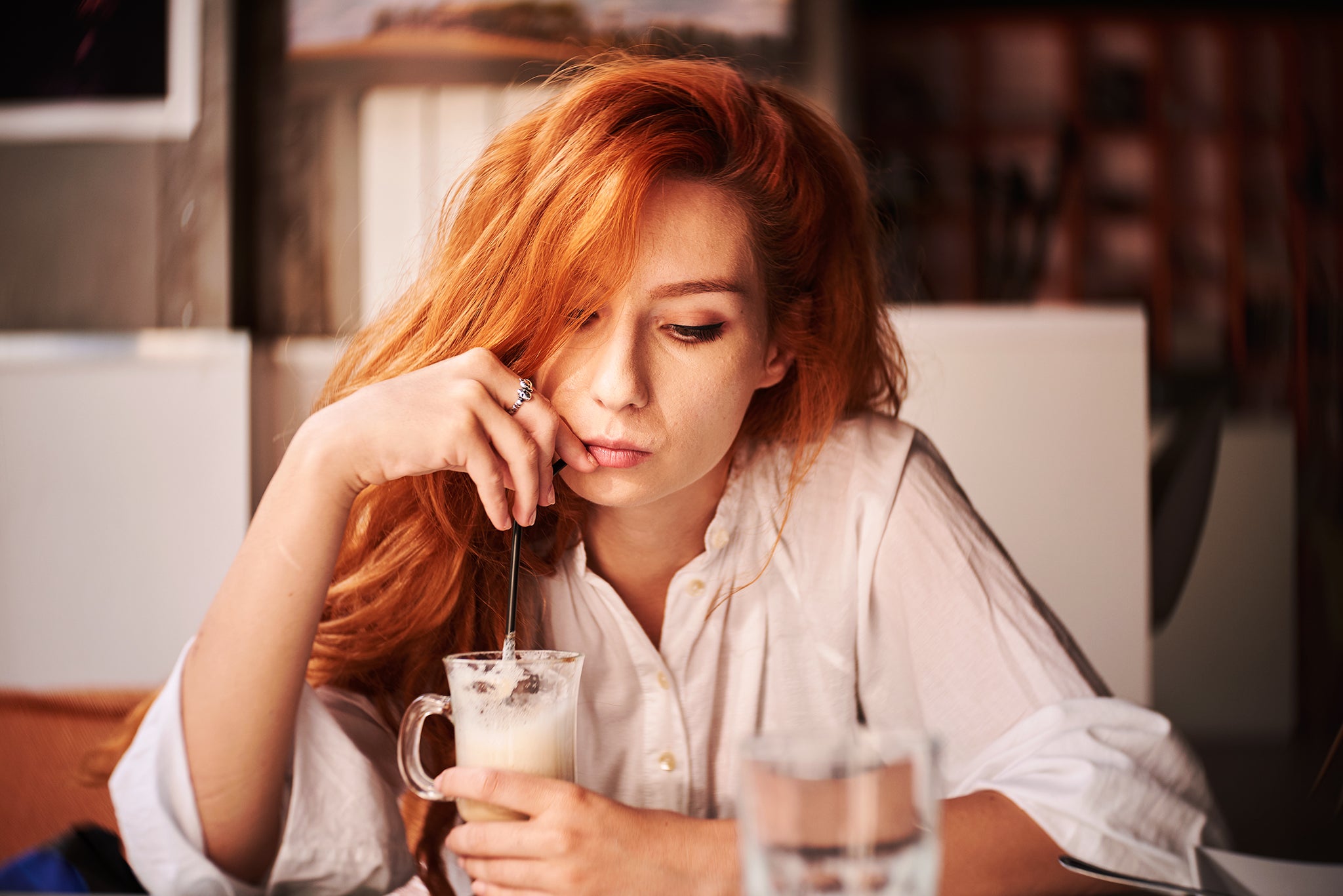 Woman with red hair drinking out of a straw at a diner