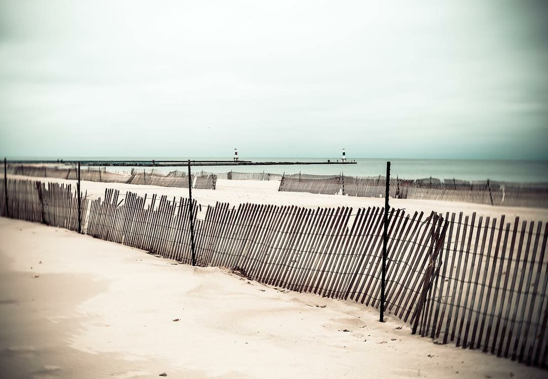 beach with fence falling down green water hazy sky featured photos