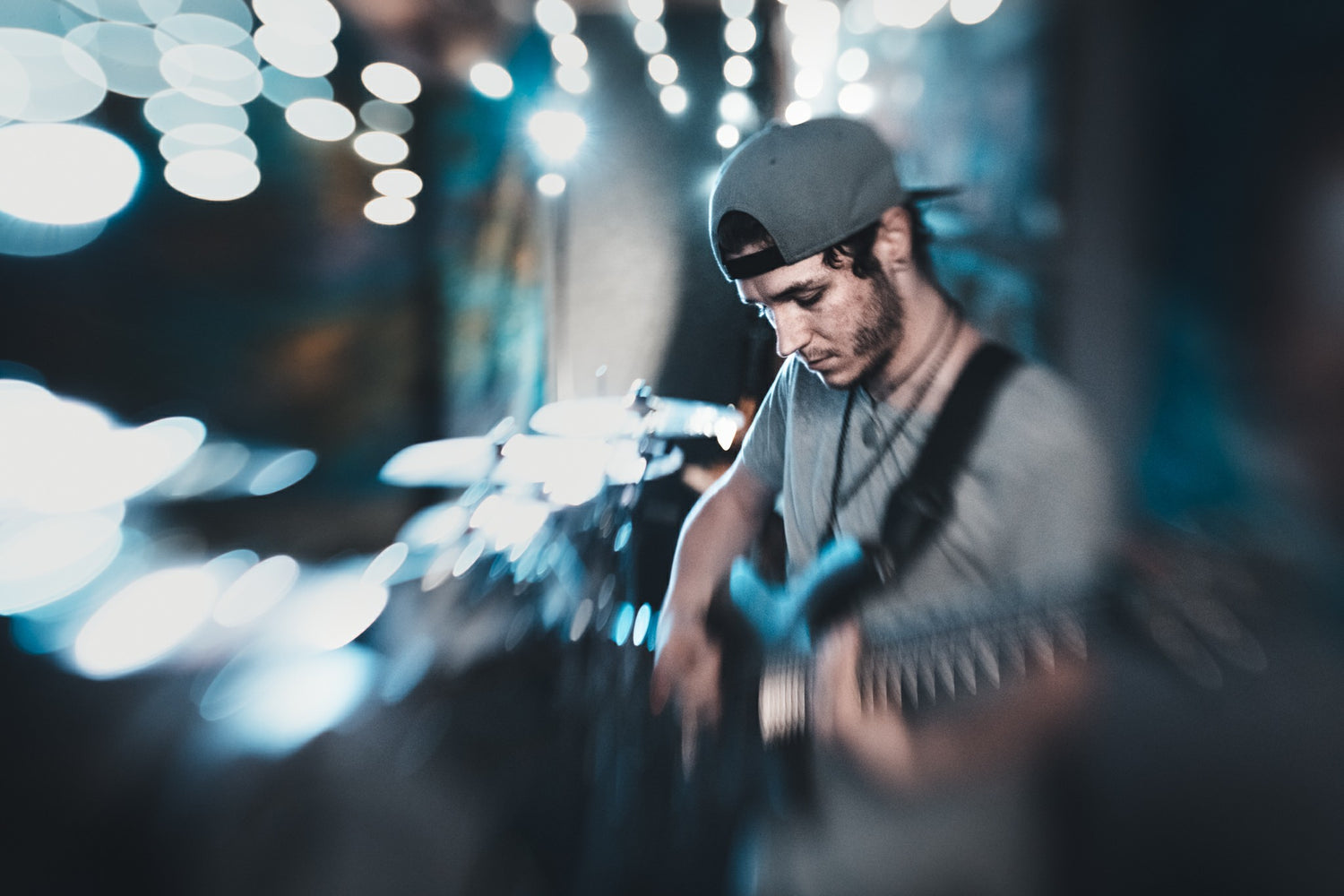 musician concert guitarist man with guitar on stage backwards hat beard selective focus blue lights Lensbaby featured photos